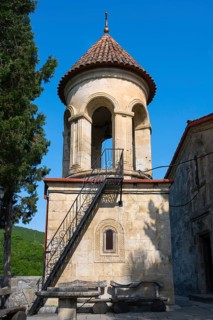 Round church tower with stone steps and red roof, immersed in quiet rural surroundings, Motsameta