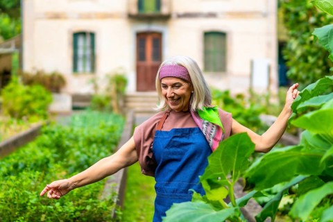Senior woman with gray hair and colorful headband smiling while standing in her flourishing home