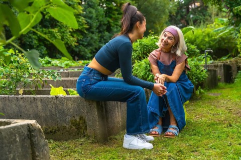 Two smiling women, a mother and daughter, enjoying a conversation outdoors, strengthening their