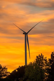 Stationary wind turbine, wind turbine, rotor blades and generator, silhouette, atmospheric sky in