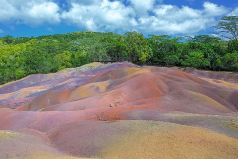 Bright red hills against thick tropical greenery under a clear sky in Mauritius. Africa, East