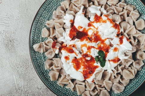 The dish features a generous serving of Turkish dumplings topped with velvety yogurt and a drizzle