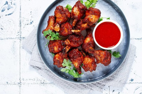 Crispy pieces of fried chicken, on a plate with sauce and herbs, in a modern kitchen environment,