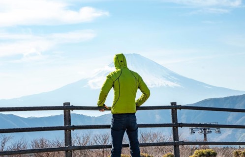 Tourist enjoying the view of the snow-covered summit of Mount Fuji volcano in spring, Owakudani,