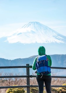 Tourist enjoying the view of the snow-covered summit of Mount Fuji volcano in spring, Owakudani,