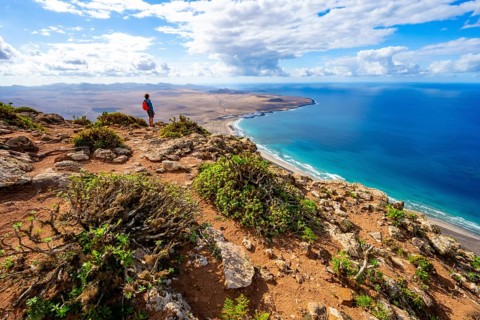 Tourist at Castillejo viewpoint, view from the Risco de Famara cliffs of the coast and the sea with
