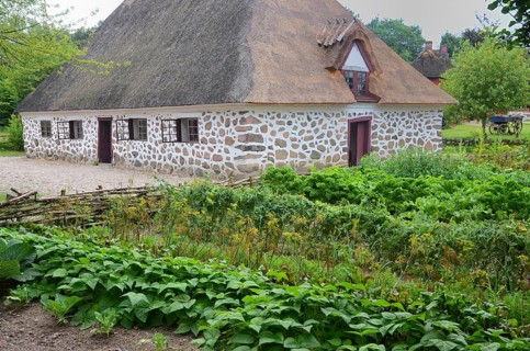 Stone house with thatched roof by older kitchen garden in Den gamle by, The old village, open air