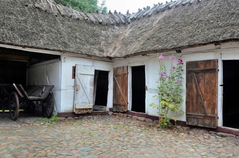 Old farmhouse with thatched roof and stone paving in Den gamle by, The old village, open air museum