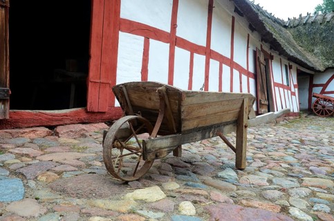 Old-fashioned wheelbarrow on paving stones and at half-timbered house in Den gamle by, The old