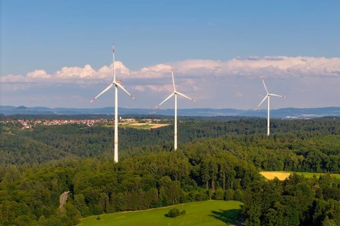 Three wind turbines on a hill in a rural landscape with forests and meadows, near Schorndorf,
