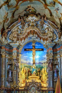 An old Baroque altar with a crucified Jesus, full of colors and images, in the Sanctuary of Bom