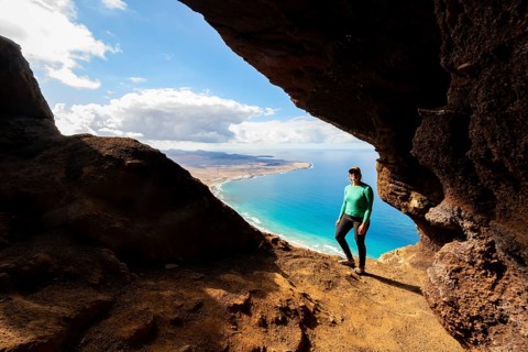 Tourist in the Cueva de las Cabras cave, young woman enjoying the view from the Risco de Famara