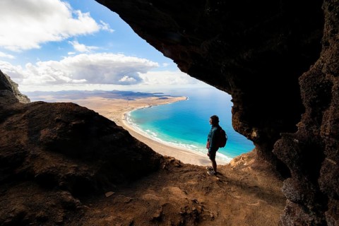Tourist in the Cueva de las Cabras cave, old woman enjoying the view from the Risco de Famara