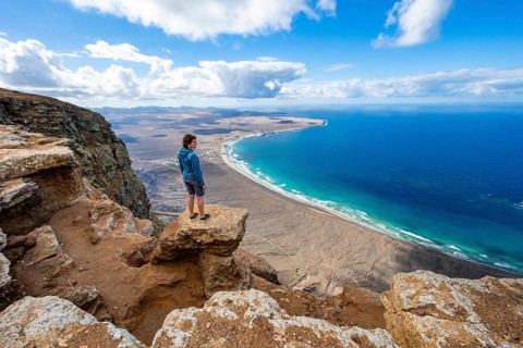 Woman enjoying the view from the Risco de Famara cliffs on Famara beach, Playa de Famara with La