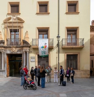 Tour guide and group of people outside museum of sacred art building, cathedral square, Teruel,