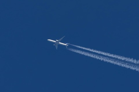 Boeing jet passenger aircraft of United airways airlines flying in a blue sky with contrails or