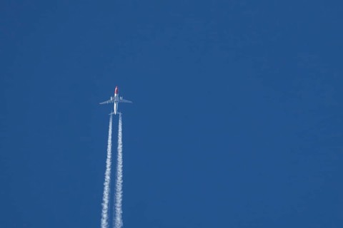 Boeing 737 jet passenger aircraft of Norwegian Air airlines flying in a blue sky with contrails or