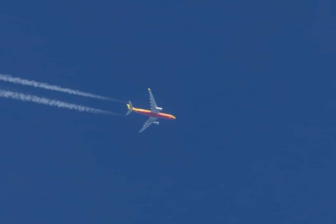Boeing 767 jet cargo aircraft of DHL airlines flying in a blue sky with contrails or vapours trails