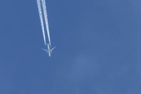 Boeing 777 jet passenger aircraft of Qatar airways airlines flying in a blue sky with contrails or