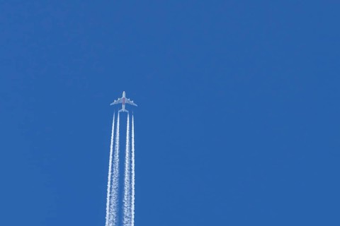 Airbus A380 jet passenger aircraft of Emirates airlines flying in a blue sky with contrails or