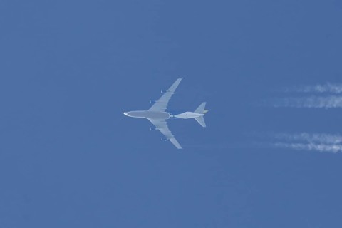 Boeing 747 jumbo jet cargo aircraft flying in a blue sky with contrails or vapour trails behind,