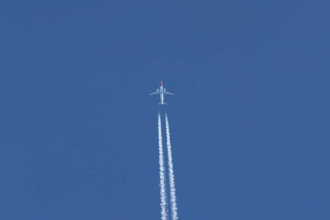 Boeing 737 jet passenger aircraft of Norwegian Air airlines flying in a blue sky with contrails or