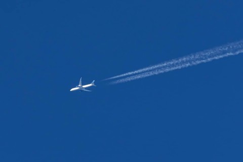 Boeing jet passenger aircraft of United airways airlines flying in a blue sky with contrails or