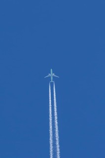 Boeing jet passenger aircraft flying in a blue sky with contrails or vapour trails behind, England,