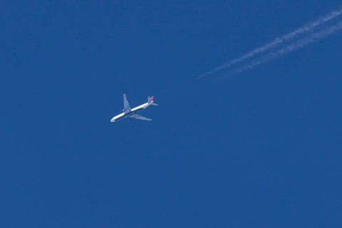 Boeing jet passenger aircraft of Delta airways airlines flying in a blue sky with contrails or