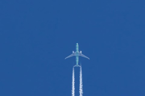 Boeing jet passenger aircraft flying in a blue sky with contrails or vapour trails behind, England,