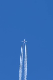 Airbus A380 jet passenger aircraft of Emirates airlines flying in a blue sky with contrails or