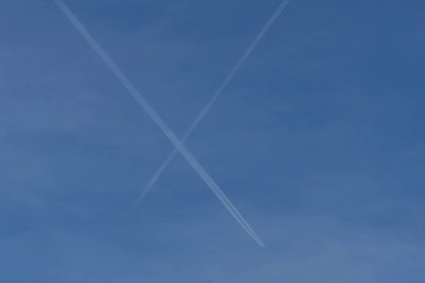 Aircraft contrails or vapour trails crossing in a blue sky, England, United Kingdom
