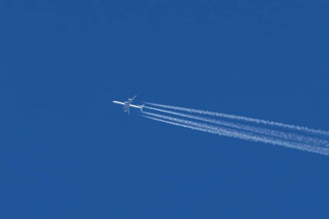 Airbus A340 jet passenger aircraft of Lufthansa airlines flying in a blue sky with contrails or