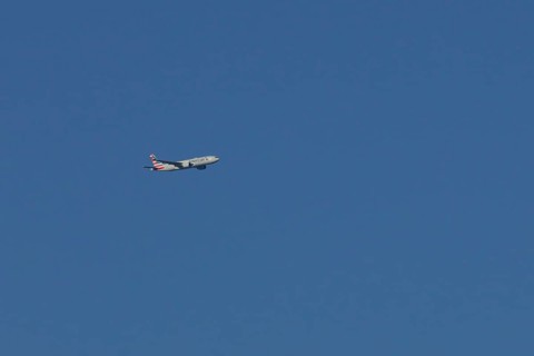 Boeing 777 jet passenger aircraft of American airlines flying in a blue sky, England, United