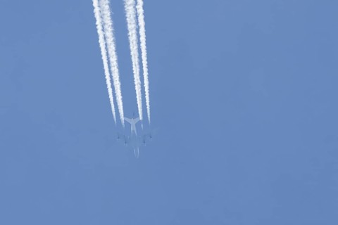 Boeing 747 jumbo jet passenger aircraft of Lufthansa airlines flying in a blue sky with contrails