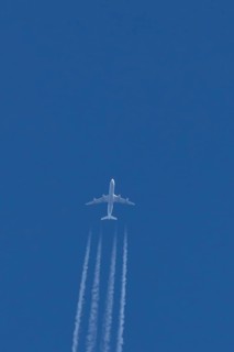 Jet commercial passenger aircraft flying in a blue sky with contrails or vapour trails behind,