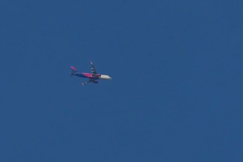 Airbus jet passenger aircraft of Wizz Air airlines flying in a blue sky, England, United Kingdom