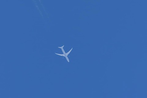 Boeing jet passenger aircraft flying in a blue sky with contrails or vapour trails behind, England,