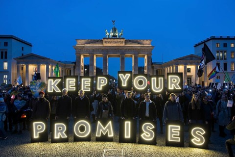 Participants hold glowing letters with the words Keep Your Promises at the international climate