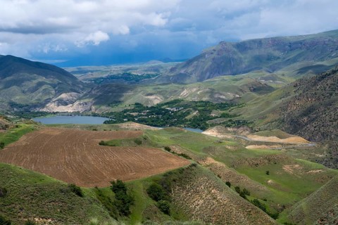 Mountains and valleys with agricultural fields under cloudy sky, landscape with Shamb reservoir