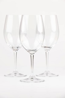 Three elegant, transparent wine glasses with long stems against a neutral background