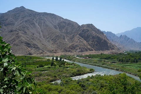 A river crosses a green valley surrounded by rugged mountains, view of Iran, Aras river near