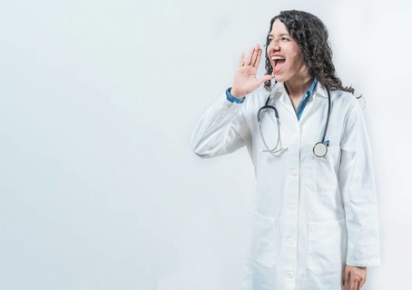 Female doctor shouting an announcement isolated. Young doctor shouting a promotion on isolated