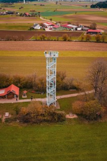An observation tower in the middle of a rural landscape with fields and buildings, surrounded by