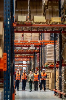 Diverse logistics team standing together in a large modern distribution warehouse, supervising
