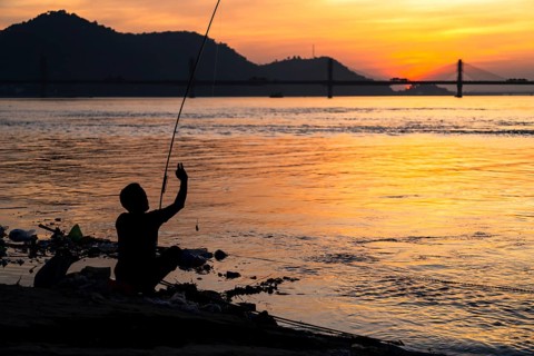 A person fishing in the river Brahmaputra during sunset, on November 4, 2025 in Guwahati, India