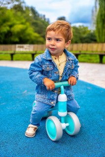 Cheerful toddler riding a balance bike in a vibrant playground, developing motor skills and