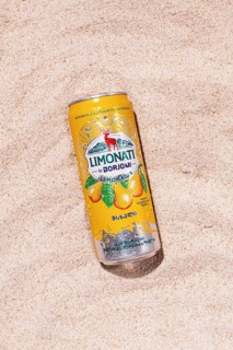 Carbonated lemonade with pear flavor, in an iron jar, Georgian drink, Borjomi, on a sandy beach,