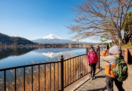 Tourists take pictures on the waterfront, Volcano Mt. Fuji is reflected in Lake Kawaguchi,