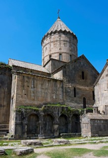 Monumental monastery complex with characteristic tower and stone architecture under a blue sky,